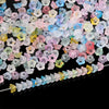 A close-up view of a 50-piece set of gradient bellflower acrylic beads in various pastel colors scattered on a dark surface.