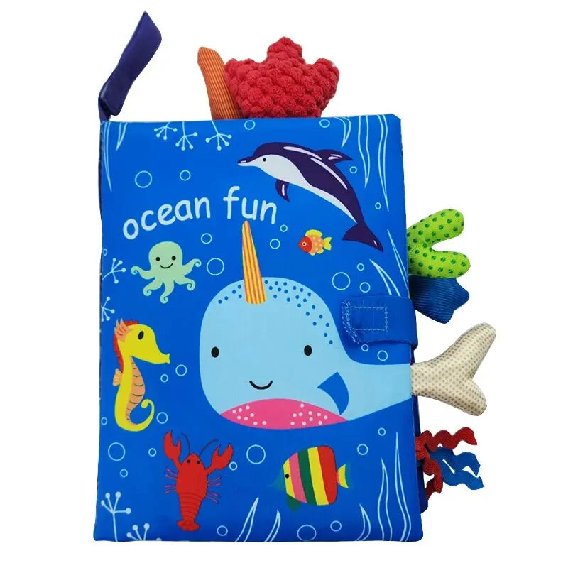 A blue sensory cloth book featuring an ocean theme with a whale, fish, and sea creatures.