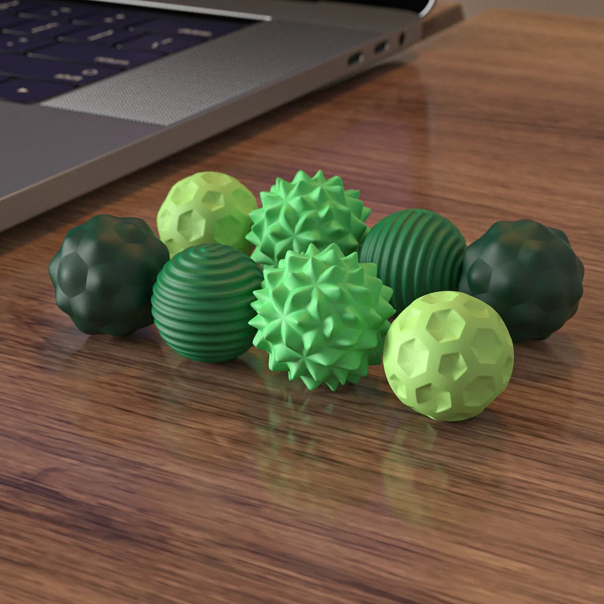 A collection of soft, textured silicone massage balls in various shades of green are arranged on a wooden surface.