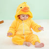 A baby wearing a yellow hooded romper resembling a chick, sitting on a white surface.