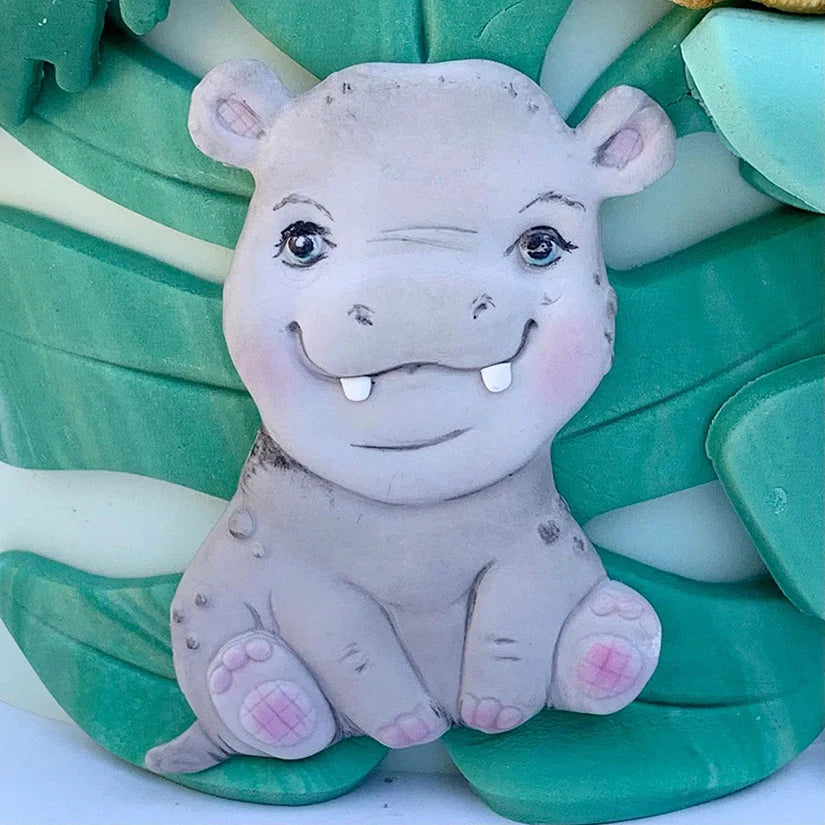 A cute gray elephant silicone baking mold for cookies and cupcakes resting on green leaves.