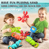 A young girl and boy are playing with a set of red crab claw pliers and green dinosaur digging tools on the beach.