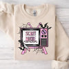 A light beige long-sleeve shirt featuring a graphic of a television screen with bats and spiderwebs.