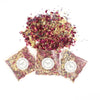 A pile of dried deep red rose petals and confetti scattered on a white background.