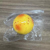 A yellow squishy potato fidget toy with orange spots is sealed in clear plastic packaging.