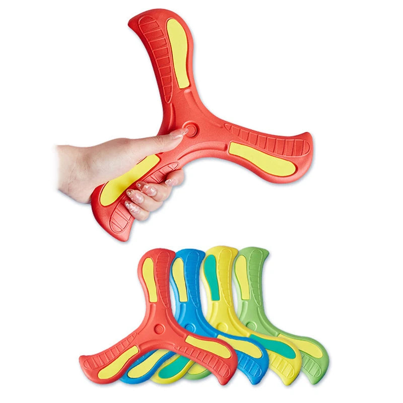 A hand is holding an orange soft foam boomerang flying disc, with several colored discs laid out below.