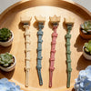 A set of baby pacifier clips with burlap flower designs arranged on a wooden tray.