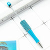 A blue beaded ballpoint pen craft kit with a silver tip rests on a white surface next to a book.