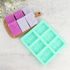 A collection of six silicone soap molds with lace patterns in various shades of purple and lilac, displayed next to a wooden 