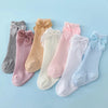 A collection of baby girl lace knee socks in various pastel colors and pinks with bows.