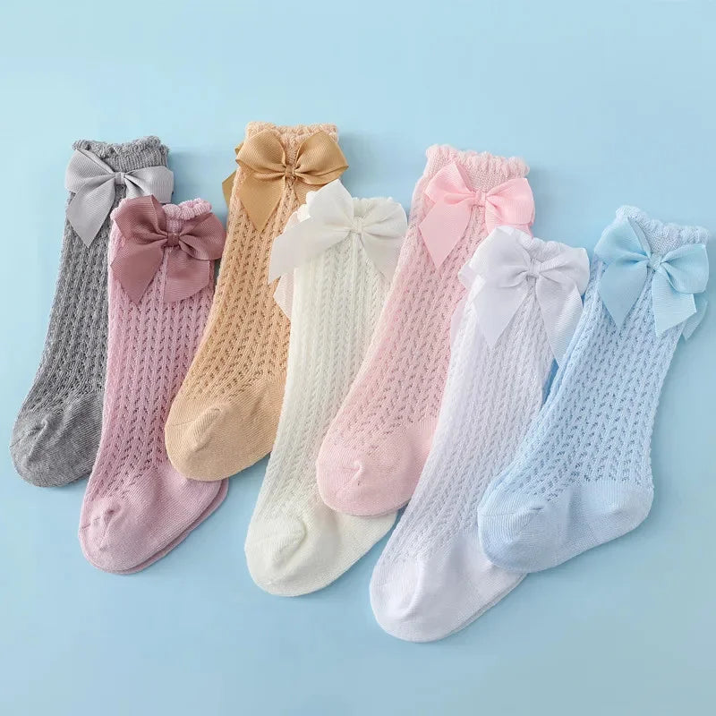 A collection of baby girl lace knee socks in various pastel colors and pinks with bows.
