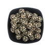 A bowl filled with small, round, black and yellow leopard print silicone beads for jewelry making.