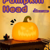 A glowing orange pumpkin head night light sits on a wooden surface with dark silhouettes of bats and trees in the background.