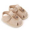 Pair of light beige soft sole sandals for baby's first steps featuring cute bear appliqués