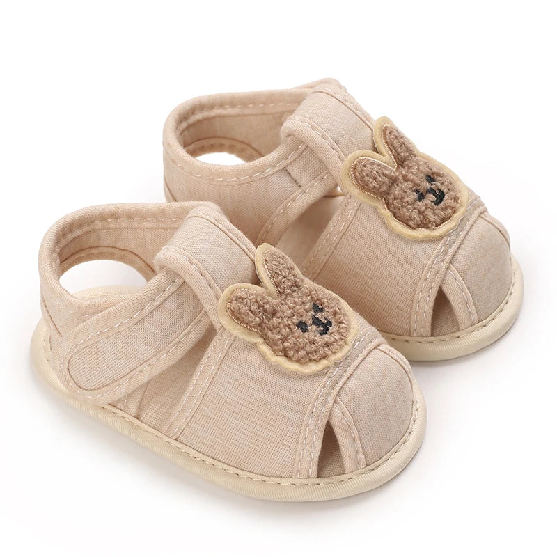 Pair of light beige soft sole sandals for baby's first steps featuring cute bear appliqués