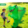 A green inflatable dinosaur punching bag is shown outdoors with a young boy playing nearby.