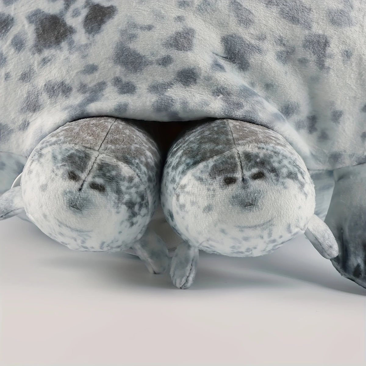A plush seal family pillow featuring a large adult seal and four small baby seals.