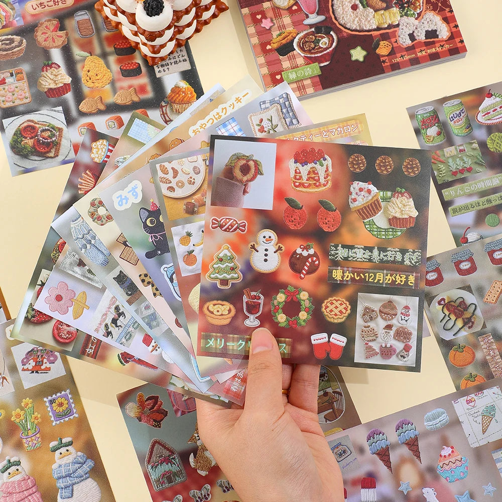 A hand holds a stack of Kawaii Embroidery-Style Sticker Book sheets featuring various cute food and seasonal designs.