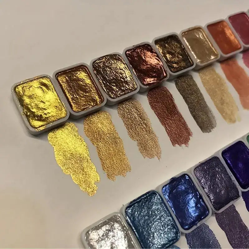 A row of 20 metal watercolor paint colors with pearl finish arranged diagonally on a white surface.