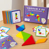 A box of Angram Kids wooden tangram puzzles and several loose colorful geometric shapes on a wooden table.