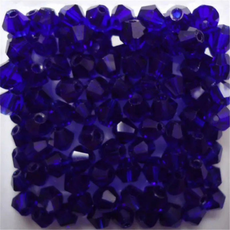 A close-up view of small, faceted deep blue glass bicone beads for jewelry making.
