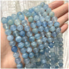 A hand holds a strand of light blue and blue-green natural stone beads for jewelry making