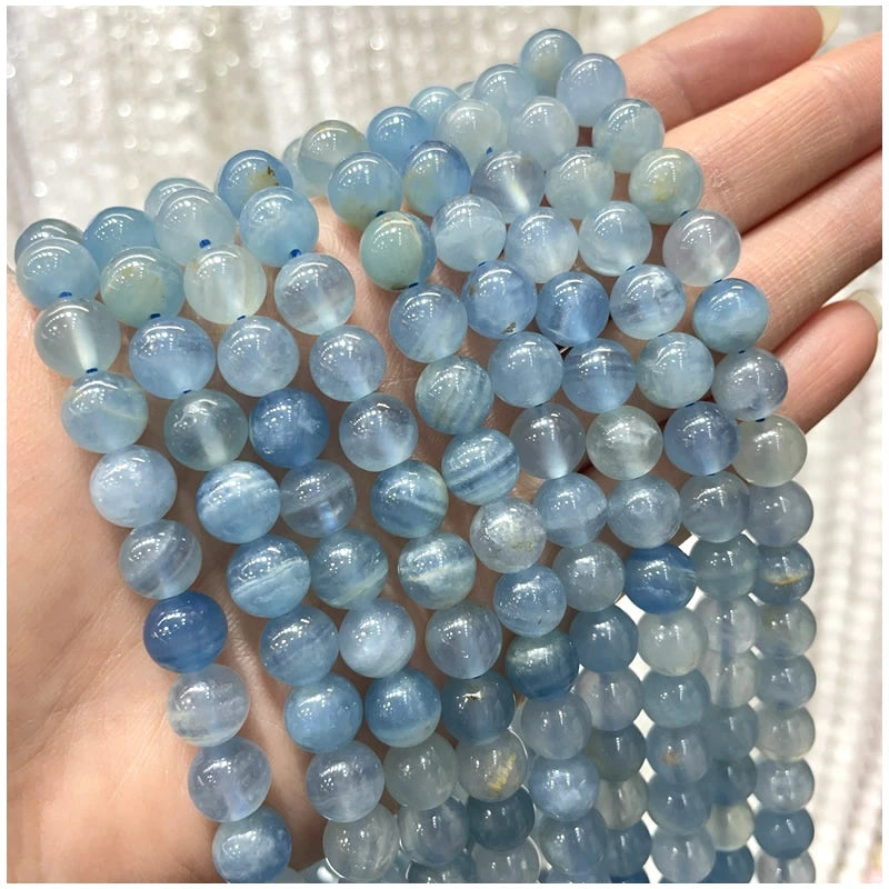 A hand holds a strand of light blue and blue-green natural stone beads for jewelry making