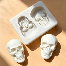 A white silicone skull cake mold is shown with a square tray and individual skulls, set against a light background.
