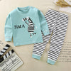 A light blue long sleeve zebra print cotton pajama set for a child lying on a beige fabric.