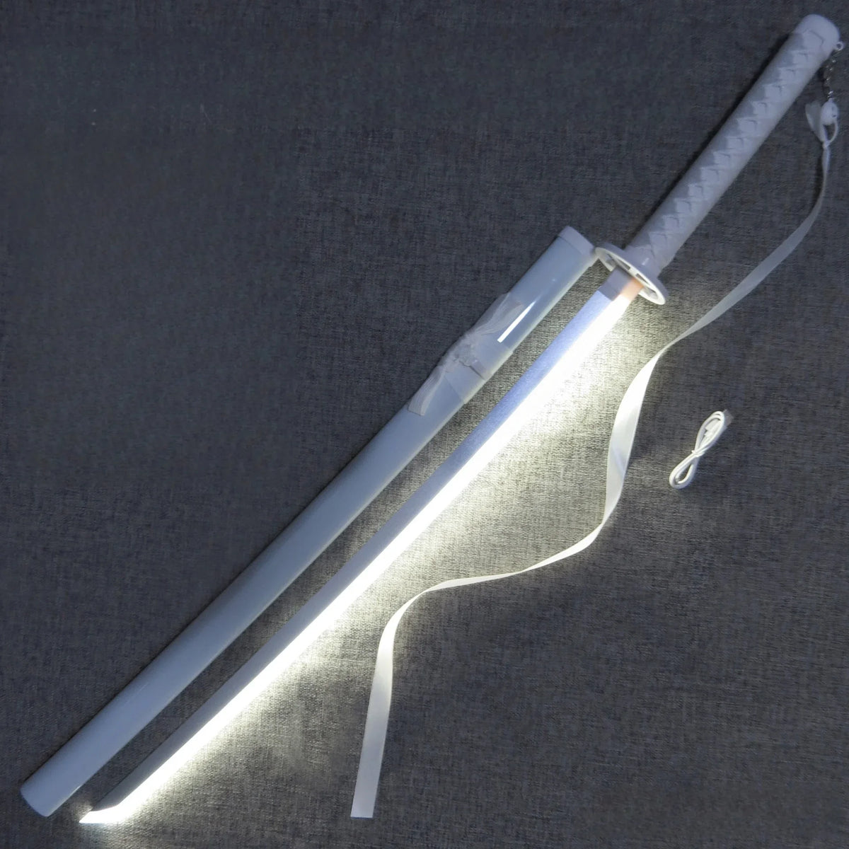 A luminous anime katana with an LED blade is displayed on a gray fabric surface.