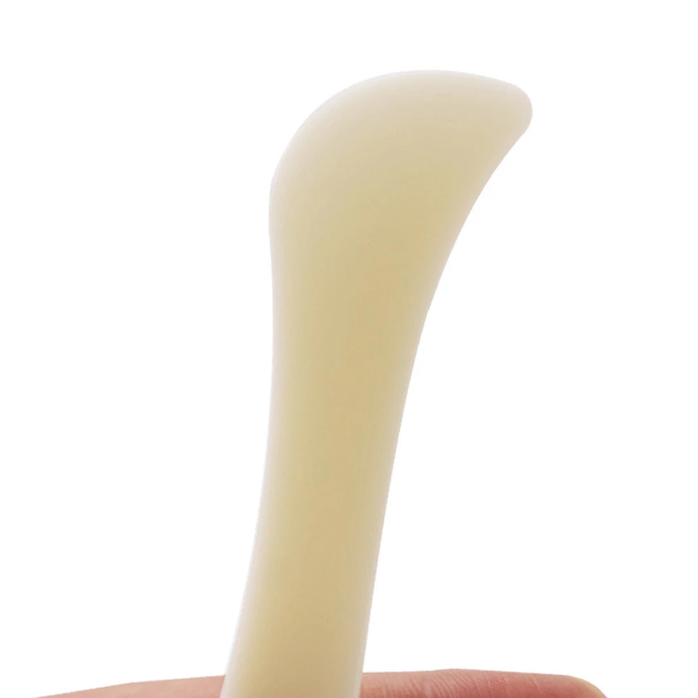 A smooth, pale yellow plastic bone folder used for paper creasing and folding crafts.