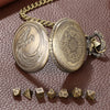 A brass steampunk dragon pocket watch dice case with seven small dice resting on a brown leather surface.
