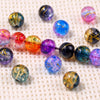 A collection of colorful gradient crystal glass beads with a golden crackle finish scattered on a white surface.