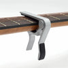 A silver aluminum alloy quick-change guitar capo clamped onto a wooden fretboard.