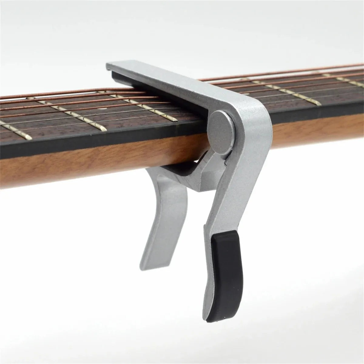 A silver aluminum alloy quick-change guitar capo clamped onto a wooden fretboard.
