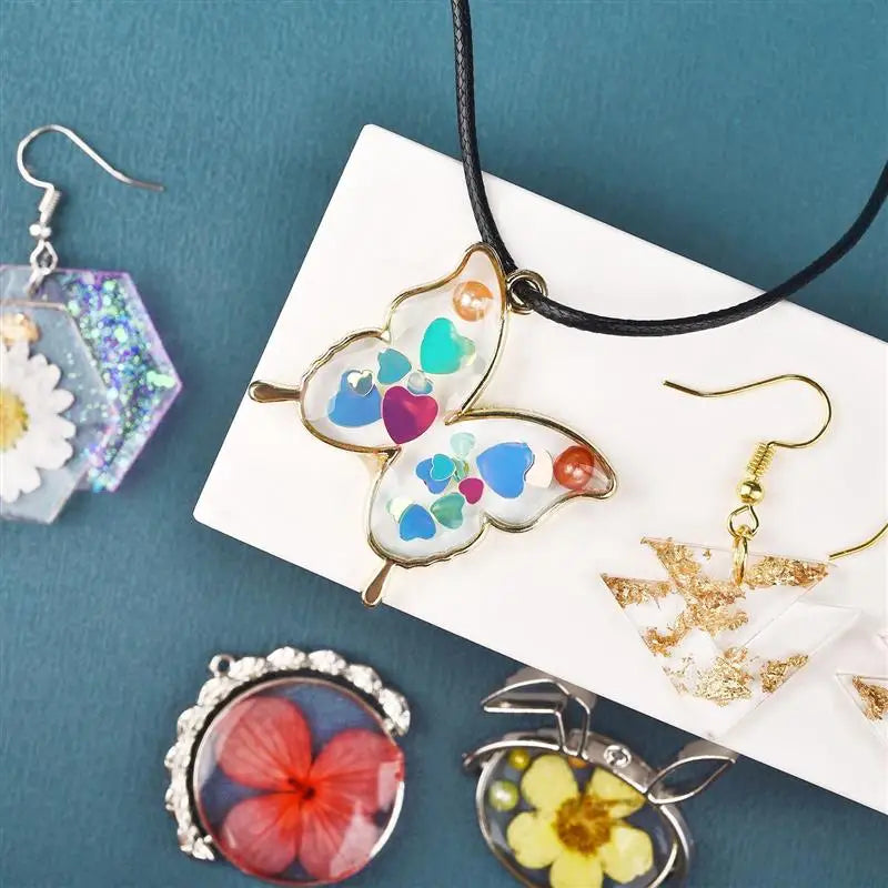 A collection of handmade jewelry featuring iridescent and floral butterfly pendants and earrings on a white card.