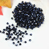 A pile of dark blue faceted crystal beads scattered on a white surface.