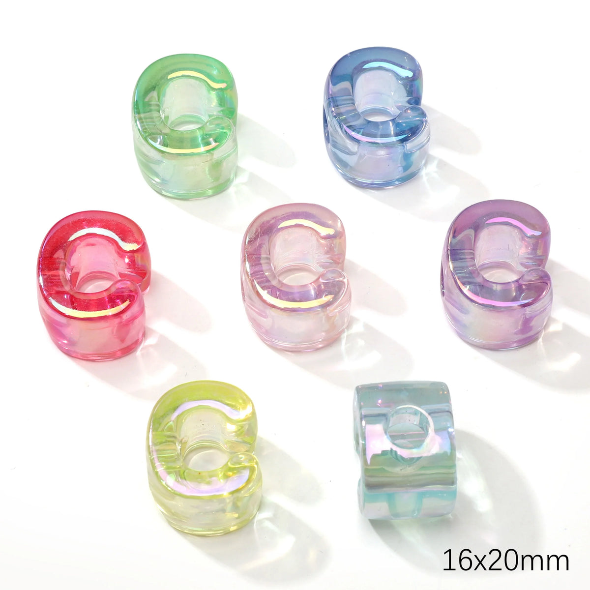 A collection of colorful, translucent acrylic alphabet beads in various shades of green, blue, and pink.