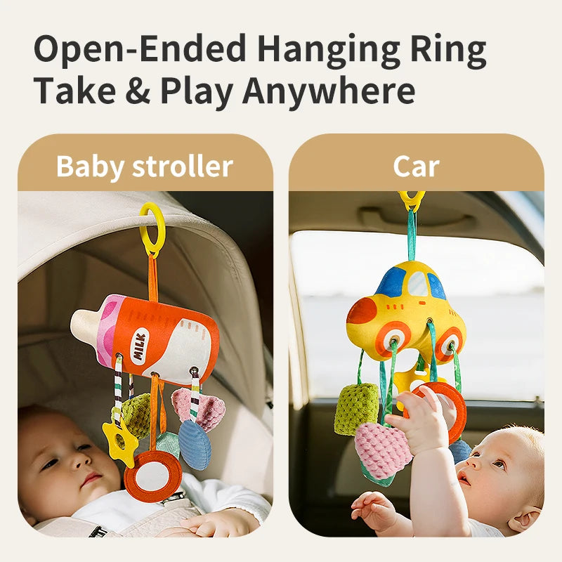 A baby is shown playing with a crab-themed rattle and teether toy hanging from a strap in a stroller or car seat.