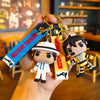 A keychain featuring a stylized figure of Michael Jackson in a dance pose, attached to a blue and black tag.
