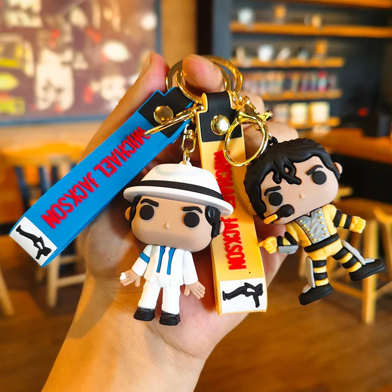 A keychain featuring a stylized figure of Michael Jackson in a dance pose, attached to a blue and black tag.