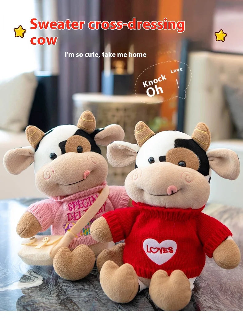 Two soft plush cow dolls dressed in sweaters, one pink and one red, displayed on a table.