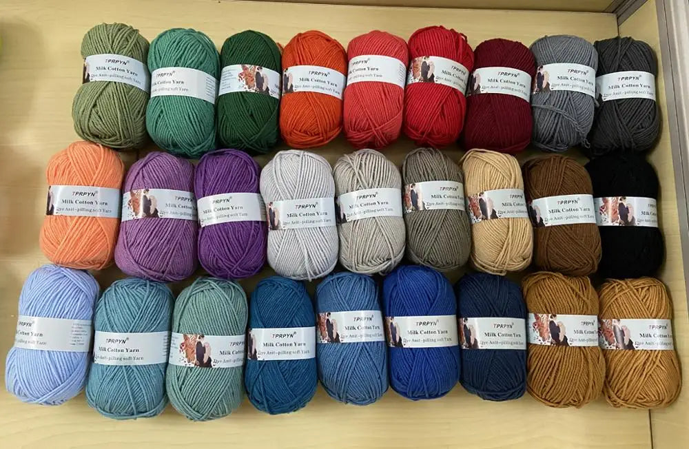 A collection of soft milk cotton yarn in various colors and textures laid out for knitting and crochet.