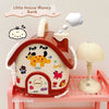 A red house-shaped piggy bank with a lock and key is shown on a pink shelf.