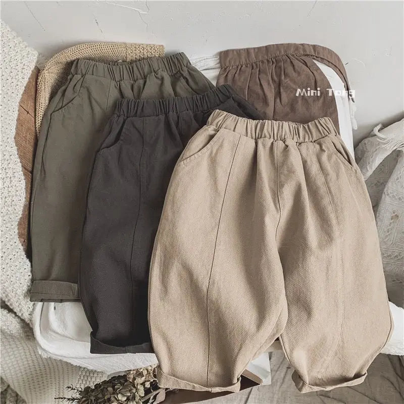A set of beige and gray loose wide-leg harem pants for boys displayed on a light background.