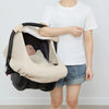A person holds a beige breathable baby car seat cover with a sun shade and mosquito net.