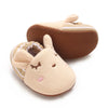 A pair of soft beige cotton baby walking shoes with anti-slip brown soles and ear flaps.