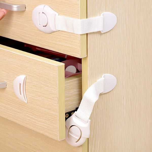 A close-up of a light wood cabinet drawer with white safety latches and hardware.