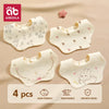 A pack of four white baby bandana bibs made of soft cotton gauze for burp cloths.