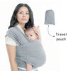 A woman is wearing a grey knitted fabric baby carrier with an attached travel pouch.